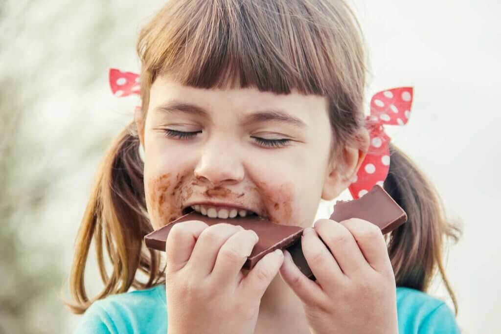 Une petite fille en train de manger du chocolat.