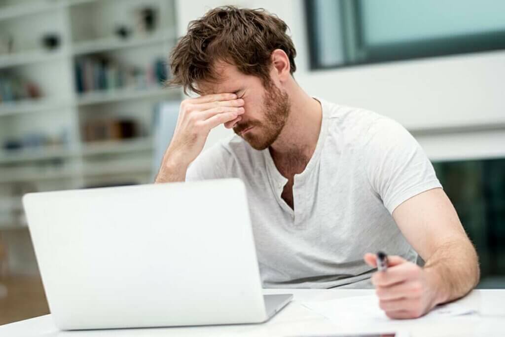 Un homme fatigué devant son ordinateur.