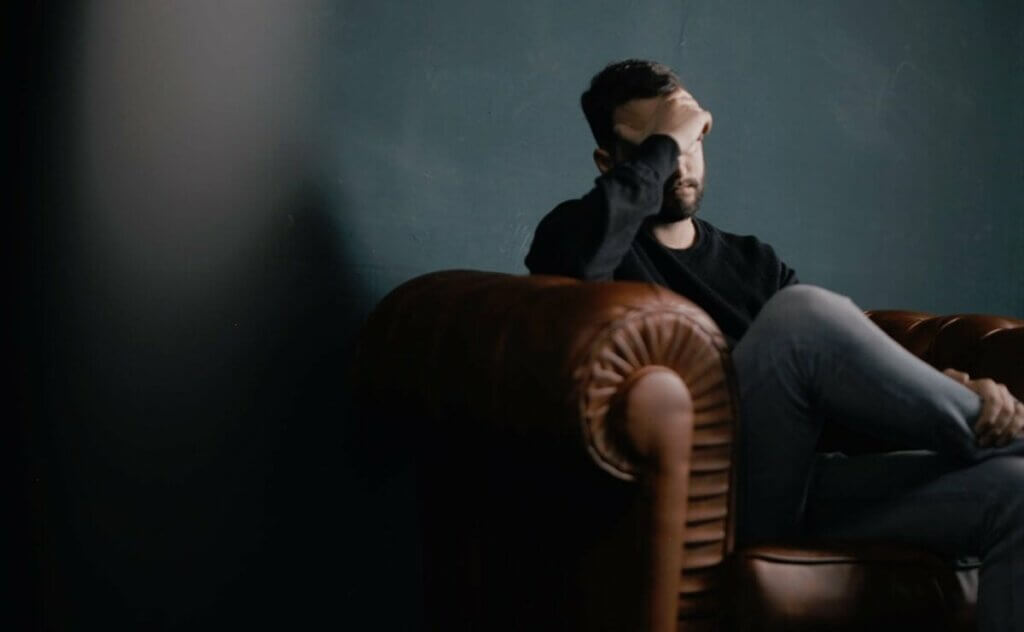 Un homme triste assis sur un canapé. 