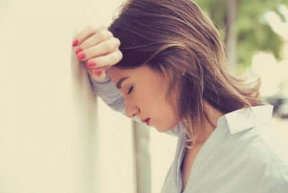 Une femme stressée qui pose sa tête contre un mur. 