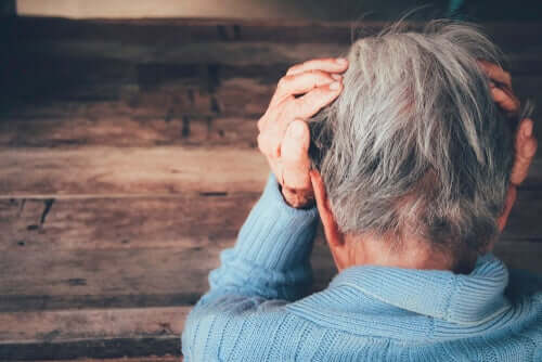 Une personne âgée, la tête entre ses mains.