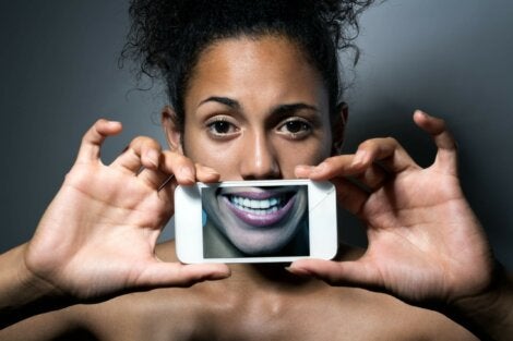 Visage d'une femme avec une photo d'un sourire sur l'écran de son téléphone. 