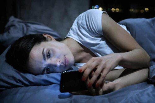 Une femme sur son portable dans le lit.