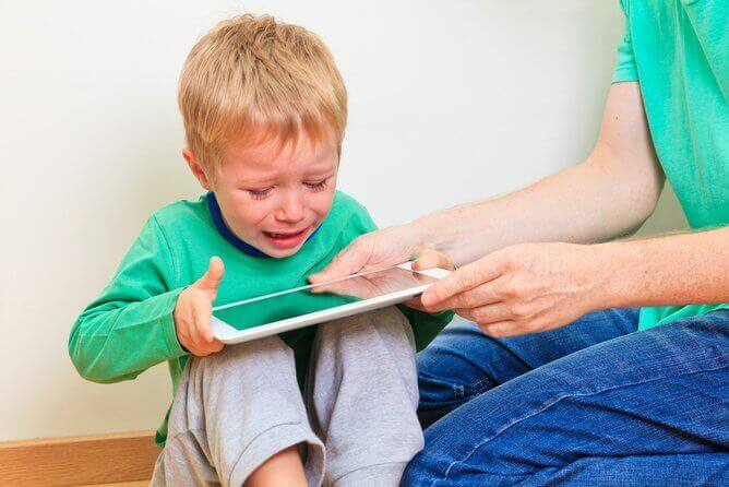 Un enfant qui pleure pour garder sa tablette. 
