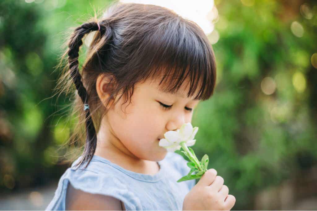 Une enfant qui sent une fleur.