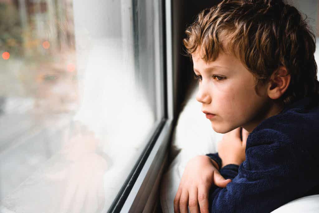 Enfant triste qui regarde par la fenêtre. 