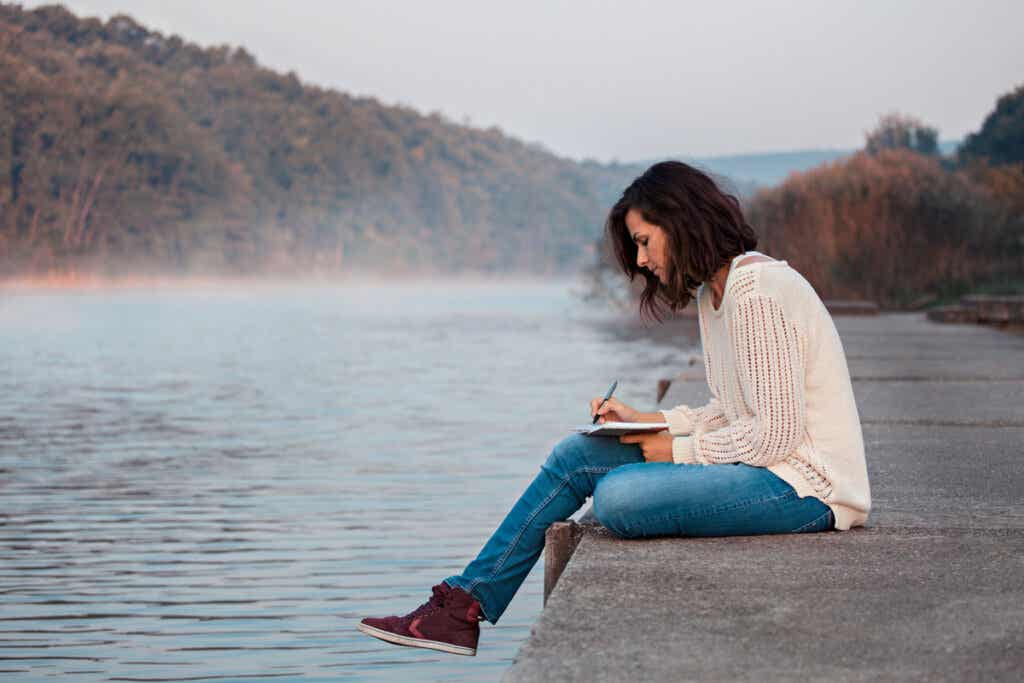 Femme qui écrit près d'un lac.