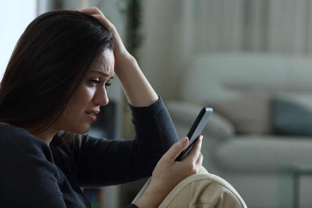 Une femme qui pleure et regarde son téléphone.