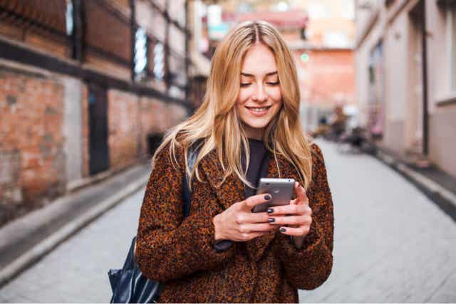 Femme sur son téléphone qui sourit.