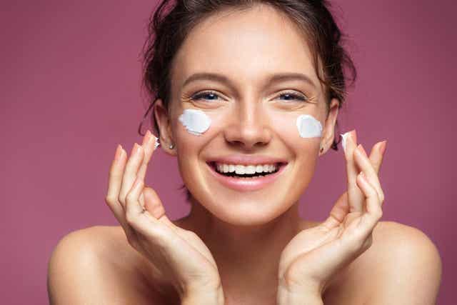 Une femme qui se met de la crème sur le visage.