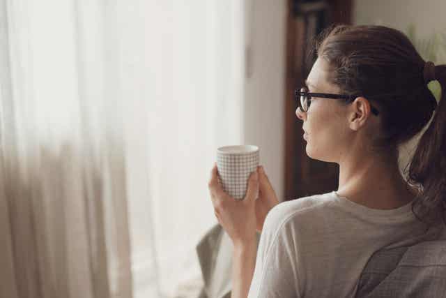 Une femme qui prend un café en regardant la fenêtre;