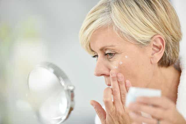 Une femme âgée qui se met de la crème sur le visage.