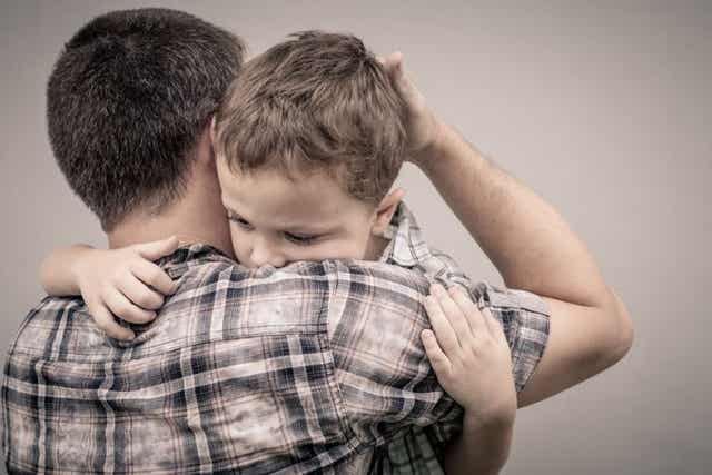 Un père qui fait un câlin à son fils. 