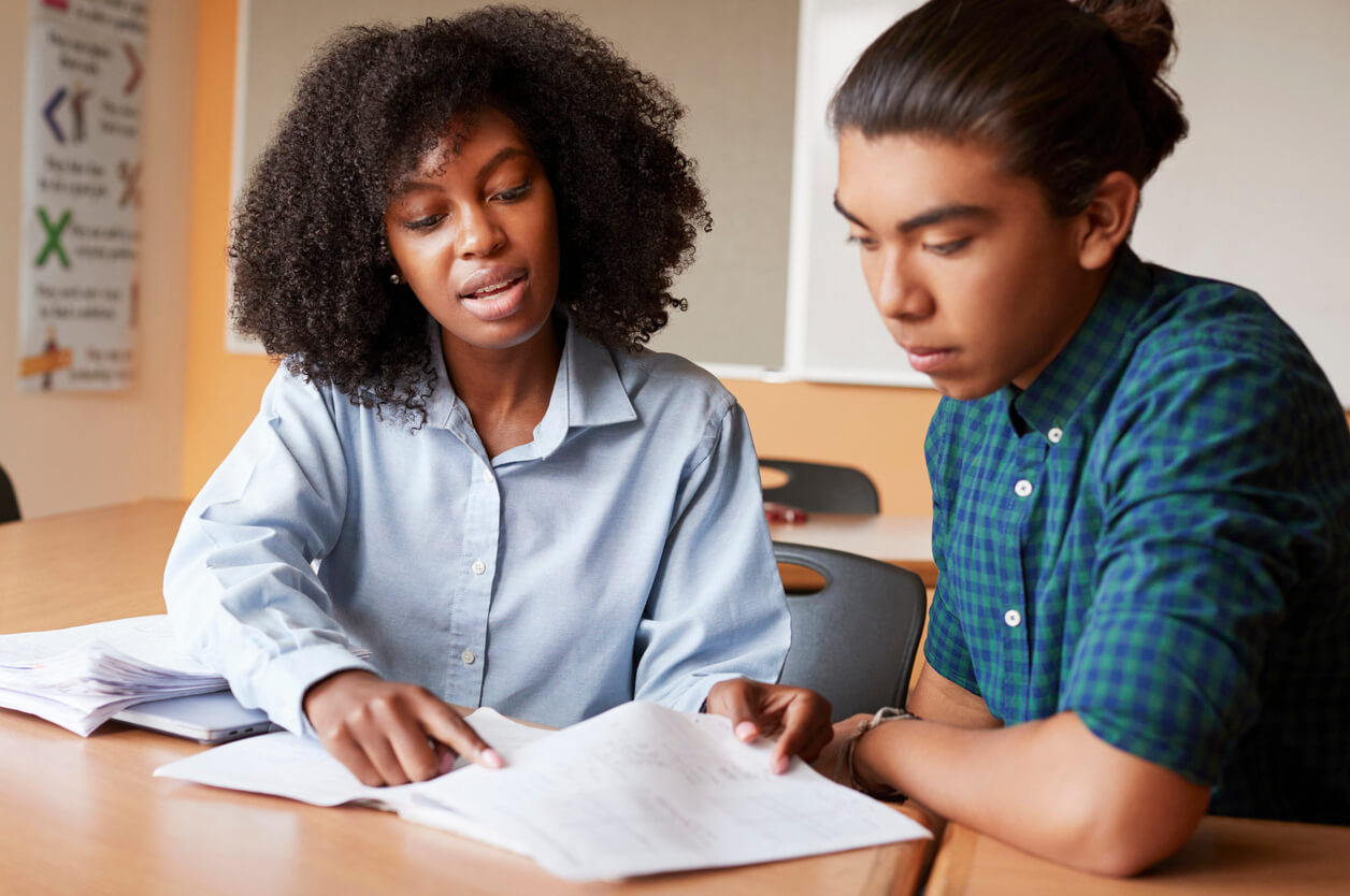 femme aidant un jeune homme à faire ses devoirs